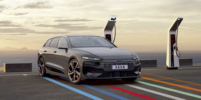 Audi A6 e-tron vor einer Ladestation bei Sonnenuntergang.