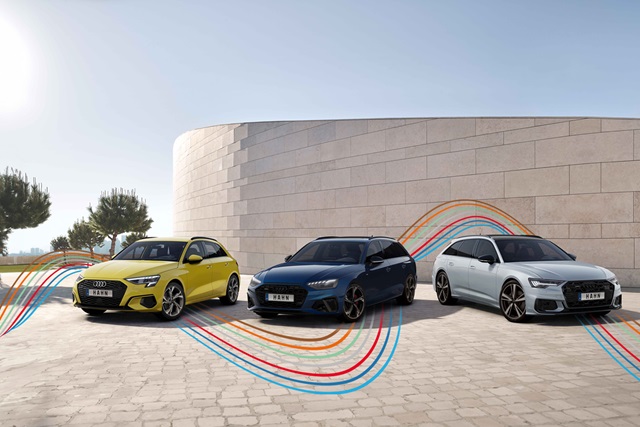 Audi Gebrauchtwagen :plus Wochen – Drei sportliche Audi-Fahrzeuge mit den bunten, dynamischen Linien des Hahn Codes vor einer Mauer.