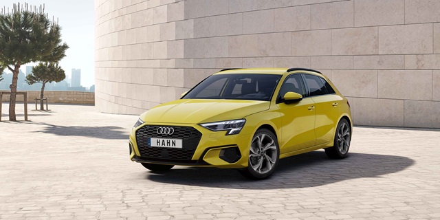 Audi Gebrauchtwagen :plus Wochen – Ein gelber Audi A3 Sportback vor einer beigen Mauer.