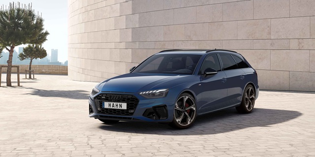 Audi Gebrauchtwagen :plus Wochen – Ein dunkelblauer Audi A4 Avant vor einer beigen Mauer.
