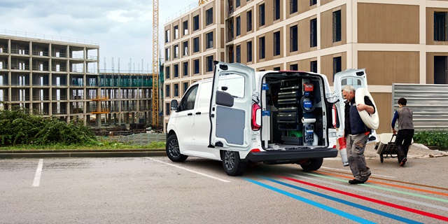 Handwerker belädt VW Transporter auf der Baustelle.